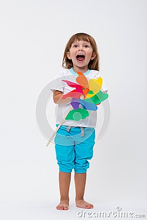 Happy smiling little girl holding a colorful toy pinwheel windmill isolated on white background Stock Photo