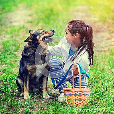 Happy smiling little girl sitting with dog on the grass Stock Photo