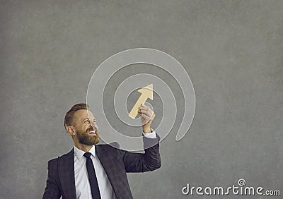 Happy businessman holding arrow going up as metaphor for business growth and success Stock Photo