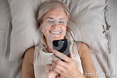 Happy smiling mature woman having fun with cellphone top view Stock Photo