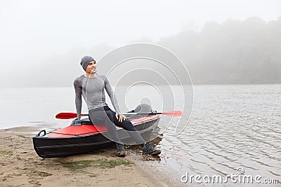 Happy smiling satisfied man having rest after padding, sitting on his boat and looking in distance, keeps his palm on his knee, Stock Photo