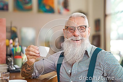 Happy smiling senior man drinking coffee in bar restaurant - Hipster trendy older male portrait Stock Photo