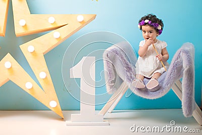 Happy smiling sweet baby girl sitting on armchair with shining light star, Birthday girl, One year old Stock Photo