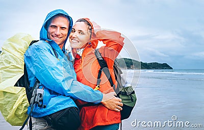 Happy smiling travelers couple in rainy day on the ocean beach Stock Photo