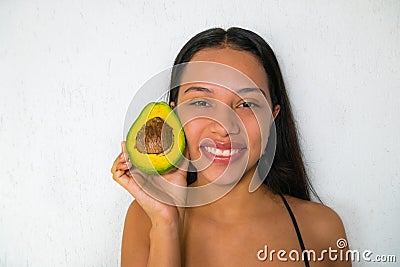 A happy and smiling woman with an avocado. Veganism and vegetarianism Stock Photo