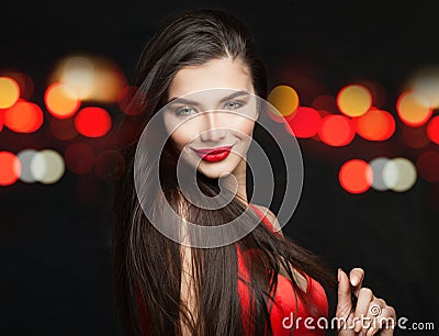 Happy smiling woman fashion model in black carnival mask, long hair and red lips makeup on black background with bokeh sparkle Stock Photo