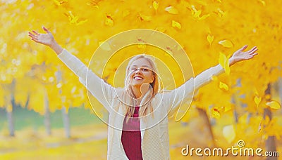 Happy smiling woman flying yellow leaves in autumn park Stock Photo