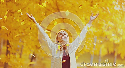 Happy smiling woman flying yellow leaves in autumn park Stock Photo