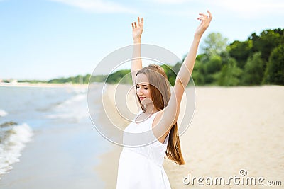 Happy smiling woman in free happiness bliss on ocean beach standing with raising hands. Portrait of a multicultural Stock Photo