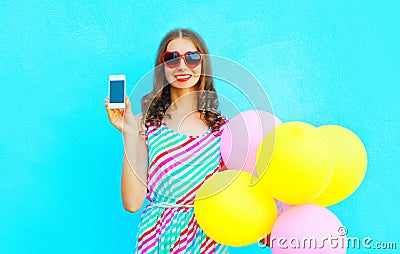 Happy smiling woman shows smartphone holding an air colorful balloons Stock Photo