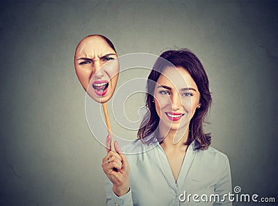 Happy woman taking off an angry mask of herself Stock Photo