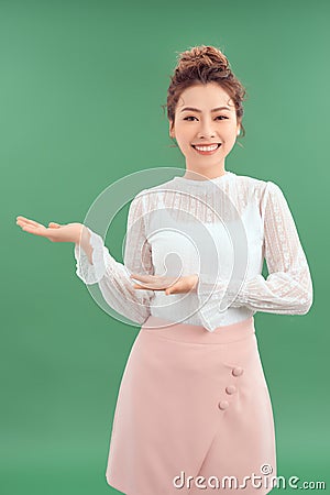 Happy smiling young beautiful business woman showing something or copyspase for product or sign text, isolated over green Stock Photo