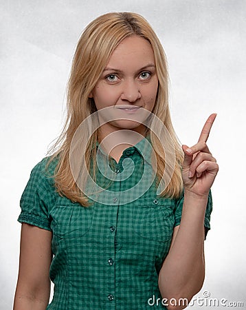 Happy and smiling young woman in casual green shirt pointing up and looking straight into camera Stock Photo