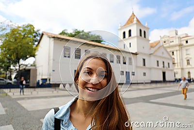 Happy smiling young woman in Sao Paulo city center with Patio do Colegio landmark on the background, Sao Paulo, Brazil Stock Photo