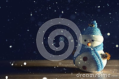 Happy snowman standing in dark winter christmas snow background. Merry christmas and happy new year greeting card with copy-space. Stock Photo