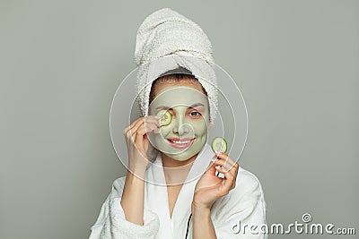 Happy spa woman in moisturizing cosmetic face mask with green organic cucumber. Facial treatment and skin care concept Stock Photo