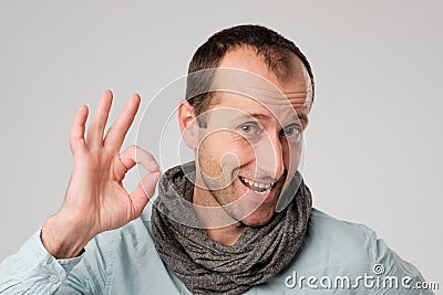 Happy spanish man shows OK against gray background. Stock Photo