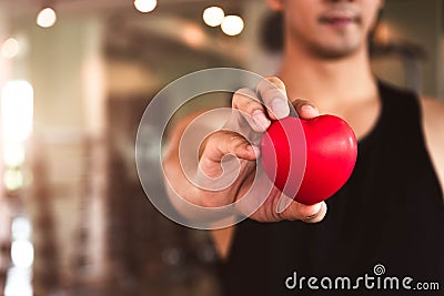 Happy sport man holding red heart in fitness gym club. Medical cardio heart strength training lifestyle. Handsome sport male Stock Photo