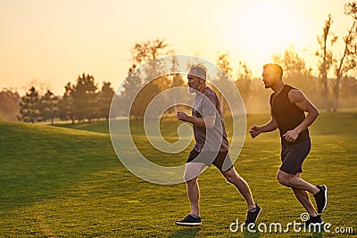 The happy sportsmen running in the beautiful park. Stock Photo