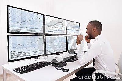 Happy Stock Market Broker Looking At Graphs On Multiple Computer Stock Photo