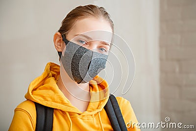Happy student on brick wall background with copy space. Young beautiful woman smiles sincerely, wearing protective mask portrait Stock Photo