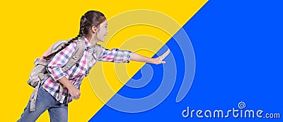 Happy student girl with school bag. Running and touching something. Isolated on yellow and blue background Stock Photo