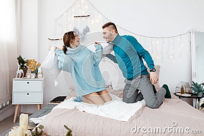 Happy stylish loving couple having a pillow fight in bed. young man and woman expecting baby for Christmas Stock Photo