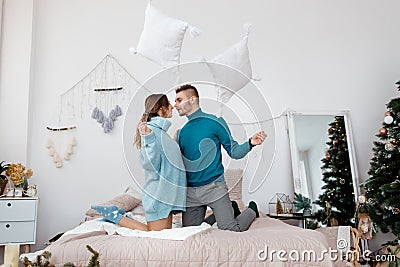 Happy stylish loving couple having a pillow fight in bed. young man and woman expecting baby for Christmas Stock Photo