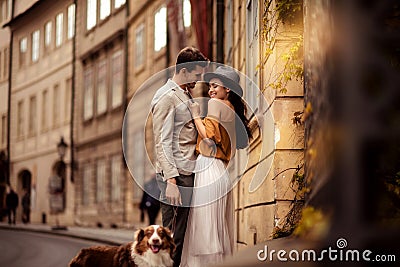 Happy stylish man strolls with dog, embraces his beautiful elegant girlfriend, have good relationship and feel true love Stock Photo
