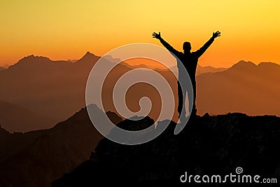 Happy success winning man on summit arms up at sunset Stock Photo