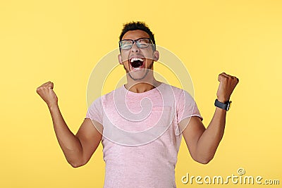 Happy successful african american young man screaming with hands up over yellow background. Stock Photo