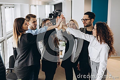 Happy successful multiracial business team giving a high fives gesture as they laugh and cheer their success Stock Photo