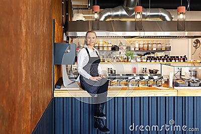 Happy successful new restaurant owner sitting on counter proud of her small business Stock Photo