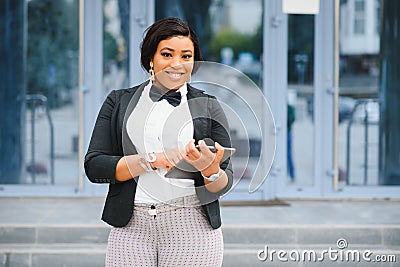 Happy successful professional posing near office building. Young African American business woman standing outside. Female business Stock Photo