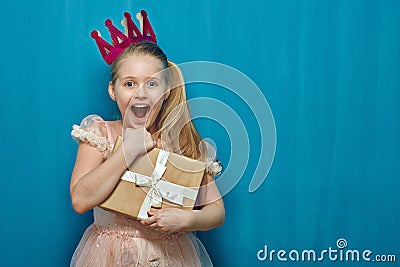 Happy surprising girl wearing pink dress and crown holding gift Stock Photo