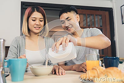 Happy sweet Asian couple having breakfast, cereal in milk, bread and drinking orange juice after wake up in the morning. Stock Photo