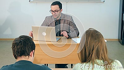 Happy teacher with laptop giving lesson to a class Stock Photo