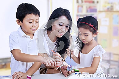 Happy teacher and preschooler paint easter eggs Stock Photo