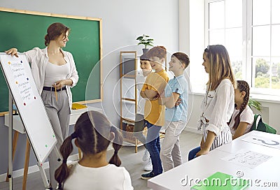 Happy school teacher uses classroom white board while making presentation for children Stock Photo