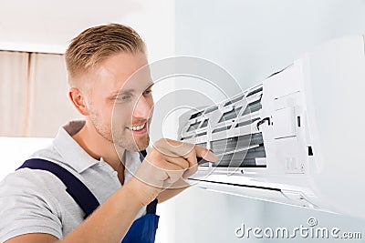 Happy Technician Repairing Air Conditioner Stock Photo