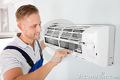 Happy Technician Repairing Air Conditioner Stock Photo