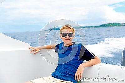 Happy teen boy in sunglasses on the yacht. Tropical sea in the b Stock Photo