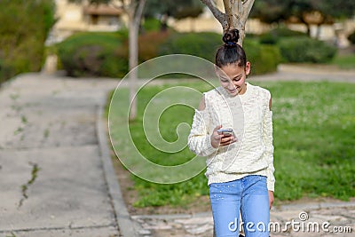 Happy teen child works in the phone, looking into it,pay goods.Teen girl young blogger reading good news on mobile phone Stock Photo