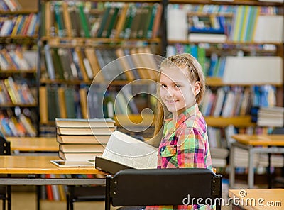 Happy teen girl with book look back in library Stock Photo