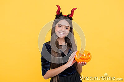 Happy teen girl wear devil horns costume holding pumpkin to create jack o lantern on halloween party, creepy halloween Stock Photo