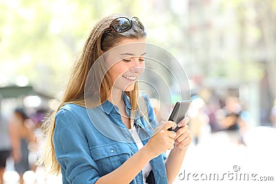 Happy teen messaging on smart phone in the street Stock Photo