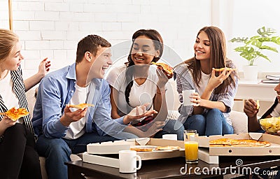 Happy teen roommates eating pizza and chatting at home Stock Photo