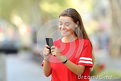 Happy teen texting on phone on the street Stock Photo