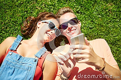 Happy teenage couple smartphone lying on grass Stock Photo