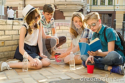 Happy 4 teenage friends or high school students reading books. Friendship and people concept Stock Photo